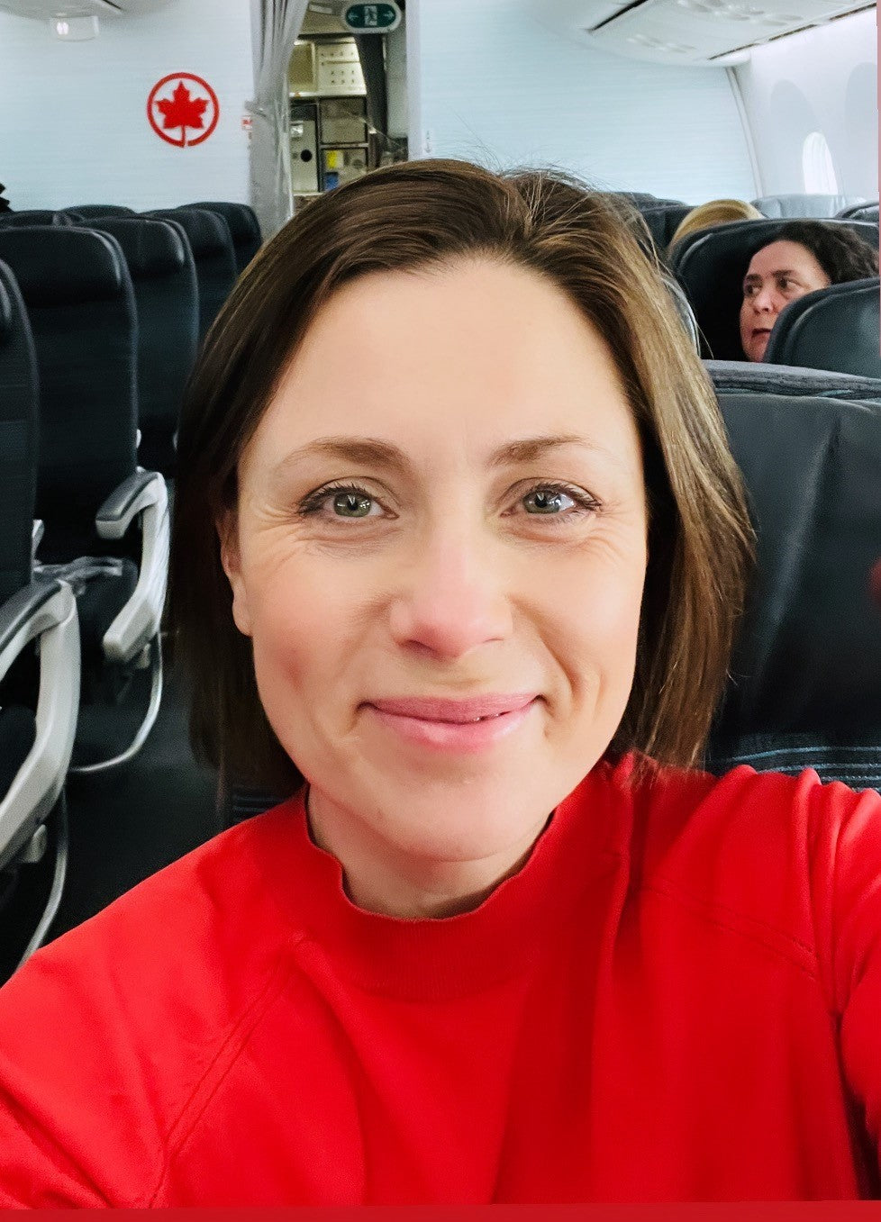 Louise smiling wearing red top on air Canada flight